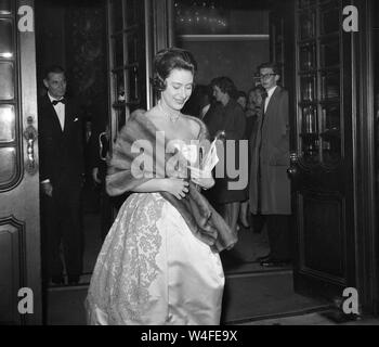 Trägt ein trägerloses Abend - Kleid, eine funkelnde Halskette und ein Fell wickeln, Prinzessin Margaret kommt an der Apollo Theater, London, Die "Stücke von acht "Revue zu sehen. Stockfoto