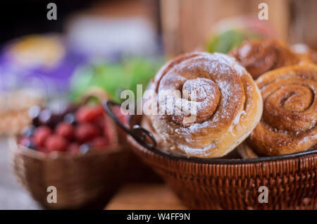 Korb mit Zimtrollen und Beeren auf Hintergrund selektiven Fokus Stockfoto