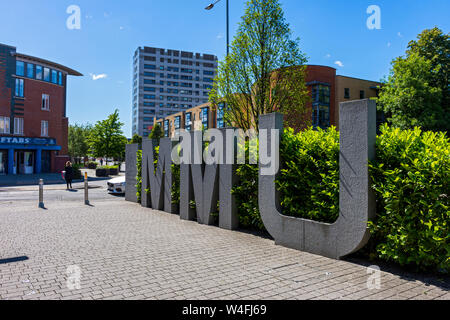 Großer Stein oder Beton MMU-Zeichen für Manchester Metropolitan University, auf einem Steg off Grenze Lane, Manchester, UK Stockfoto