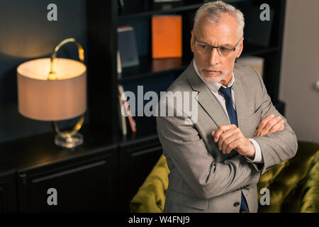 Im Wartestand. Closeup Portrait von ein ernster Mann mit verschränkten Armen im Stehen und schaut in die Ferne Stockfoto