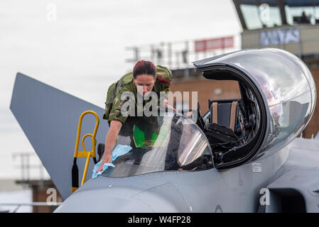 Weibliche Person der schwedischen Luftwaffe, die Cockpit-Windschutzscheibe des Gripen-Flugzeugs auf der Royal International Air Tattoo Airshow, RAF Fairford, Großbritannien, reinigt. Stockfoto