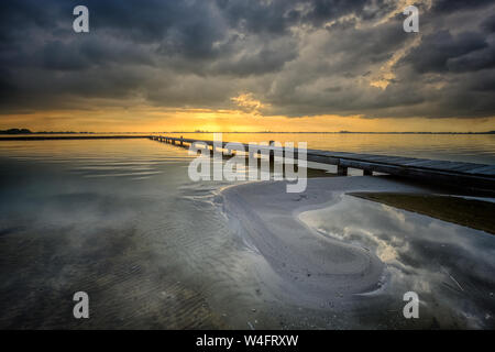 Eine marine Landschaft an einem See mit einem Bootsanleger und schöne Reflexionen der Wolken auf dem Wasser - Schildmeer, Niederlande Stockfoto