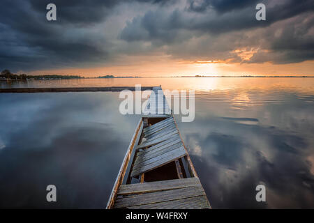 Eine marine Landschaft an einem See mit einem Bootsanleger und schöne Reflexionen der Wolken auf dem Wasser - Schildmeer, Niederlande Stockfoto