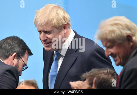 Stanley Johnson (rechts) klatscht seinen Sohn Boris Johnson (Mitte) bei der Königin Elizabeth II. in London, nachdem er als die neue konservative Parteichef angekündigt wurde, den Übergang der nächste Ministerpräsident zu werden. Stockfoto