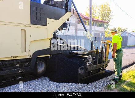 Targoviste, Rumänien - 2019. Ansicht schließen auf ein Arbeiter der Asphalt fertiger Maschine beim Straßenbau. Bau einer neuen Straße mit Unterstützung f Stockfoto