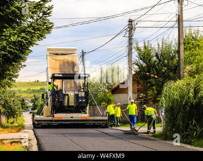 Arbeiter in der Nähe der Asphalt Maschine über den heißen Asphalt mit Schaufeln auf den Straßenbau. Stockfoto