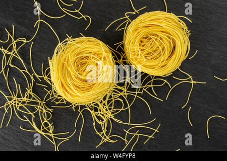 Gruppe von zwei ganze Menge Stücke der rohen Nudeln Engelshaar flatlay am grauen Stein Stockfoto