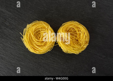 Gruppe von zwei ganze rohe Nudeln Engelshaar flatlay am grauen Stein Stockfoto