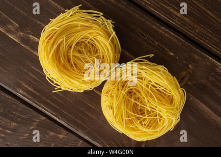 Gruppe von zwei ganze rohe Nudeln Engelshaar flatlay auf braunem Holz Stockfoto