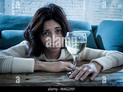 Betont und hoffnungslose junge Frau trinkt ein Glas Wein allein zu Hause. Deprimiert, frustriert und schwach, versuchen, besser trinken zu fühlen. Unhe Stockfoto