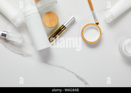 7/8-Ansicht von Creme Röhren, Kosmetik Gläser, Dispenser und Glasflasche mit Pinsel auf weiße Oberfläche Stockfoto