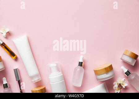 Blick von oben auf die Creme Röhren, kosmetische Dispenser, leere Gläser und mit Hand Creme, mascara Flaschen auf Rosa Stockfoto