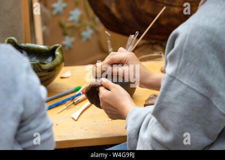 Kid Spritzguss- und bürsten Ton Cup mit einem Schwamm auf einem Workshop. Outdoor Camp Aktivitäten für Kinder Stockfoto