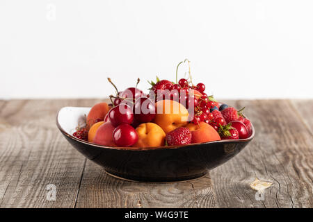Platte mit gemischten köstliche reife Beeren auf Holztisch isoliert auf weißem Stockfoto