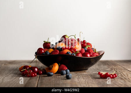Platte mit gemischten köstliche Beeren auf Holztisch isoliert auf weißem Stockfoto