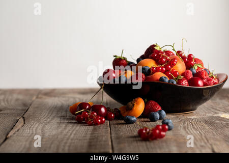 Platte mit Frischer gemischter köstliche Beeren auf Holztisch isoliert auf weißem Stockfoto