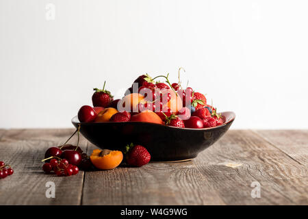 Platte mit gemischten köstliche reife Beeren auf Holztisch isoliert auf weißem Stockfoto
