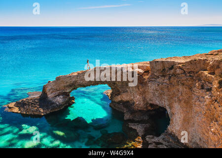 Frau auf der wunderschönen natürlichen Felsbogen in der Nähe von Ayia Napa Cavo Greco und Protaras auf Zypern Insel, Mittelmeer. Legendäre Brücke Liebhaber. Amaz Stockfoto