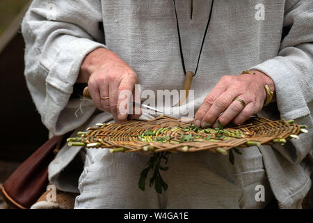 Nahaufnahme von Handwerker tragen ländliche Kleidung, Weidenkorb aus Zweigen. Traditionelle Handarbeit Webtechnik im ländlichen Dorf Stockfoto