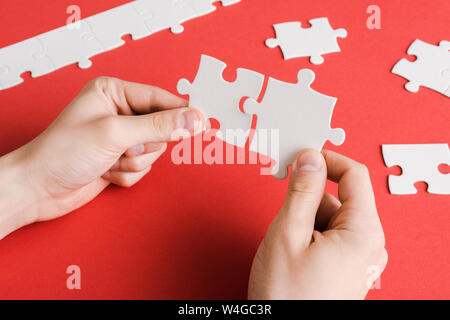 7/8-Ansicht von Mann mit weissen Puzzleteile in die Hände auf Rot Stockfoto