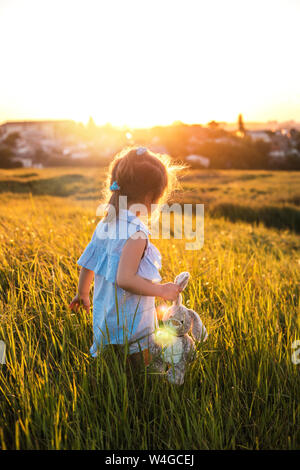 Glückliche kleine Mädchen im Sommer Feld bei Sonnenuntergang. Stockfoto