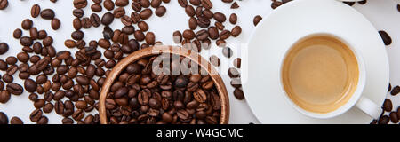 Blick von oben auf die Kaffee in der Tasse auf Untertasse in der Nähe verstreut gerösteten Bohnen und Houten, Panorama-Aufnahme ein. Stockfoto