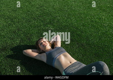 Sportlerin entspannend, liegen auf dem Rasen nach dem Workout Stockfoto