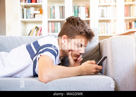 Teenager auf der Couch zu Hause liegen mit Handy Stockfoto