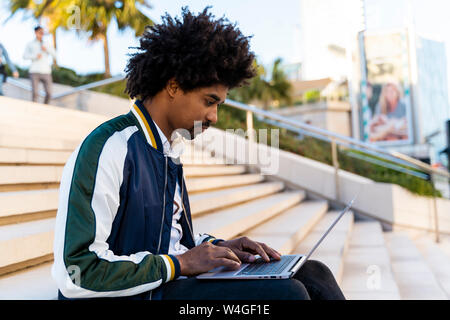 Casual Geschäftsmann auf der Treppe sitzen, Arbeiten am Laptop Stockfoto