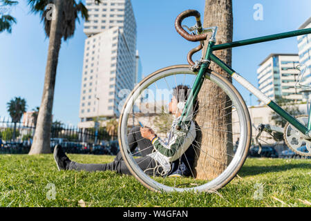 Casual Geschäftsmann mit Fahrrad eine Pause im städtischen Park Musik hören, Barcelona, Spanien Stockfoto