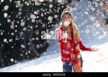 Junge blonde Frau werfen mit Schnee im Winter Stockfoto