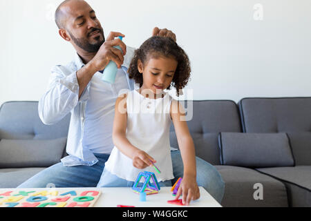 Vater tun Haare's Tochter auf der Couch zu Hause Stockfoto