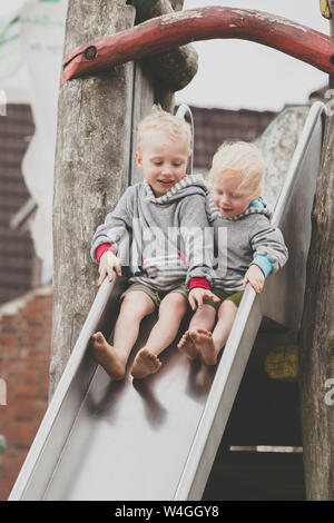 Zwei barfuß Geschwister zusammen auf einer Folie Stockfoto