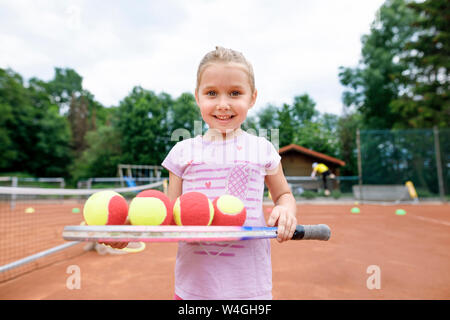 Kleines Mädchen, Lernen, Tennis zu spielen, balancieren Bälle auf einem Schläger Stockfoto