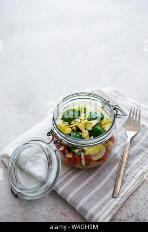 Glas Salat mit Gurken, Kichererbsen, Zwiebeln, Tomaten, Basilikum, Chia Samen und gehobelten Mandeln Stockfoto