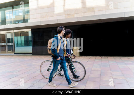 Zwei casual Geschäftsleute mit dem Fahrrad zu Fuß in die Stadt, Barcelona, Spanien Stockfoto