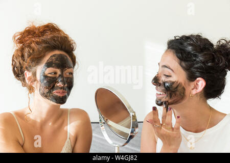 Zwei glückliche junge Frauen Anwendung Gesichtsmasken zu Hause Stockfoto