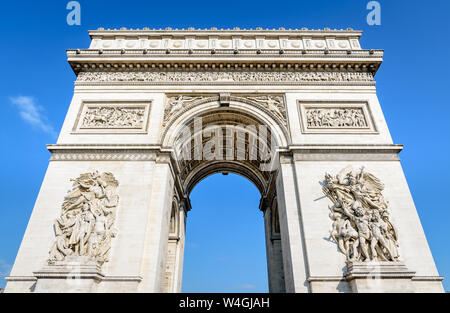 Vorderansicht der östlichen Fassade der Arc de Triomphe in Paris, Frankreich, von der Morgensonne unter einem blauen Himmel beleuchtet. Stockfoto