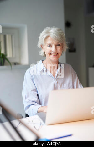 Portrait von lächelnden reife Frau mit Laptop auf dem Schreibtisch Stockfoto