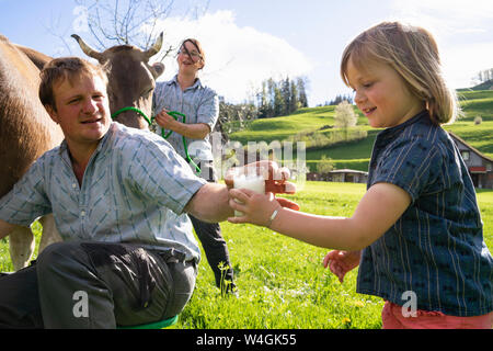 Bauer mit seiner Tochter ein Glas frische Milch von der Kuh auf der Weide Stockfoto