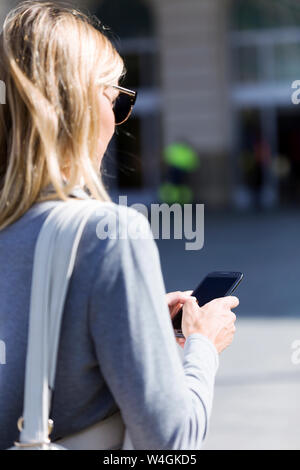 Junge Geschäftsfrau sms mit Ihrem Handy beim Gehen Stockfoto