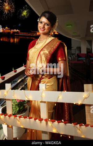 Frau, die das Diwali-Festival mit dem Goldenen Tempel im Hintergrund feiert, Amritsar, Punjab, Indien Stockfoto