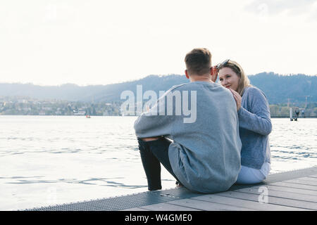 Junges Paar auf Steg am See Zürich, Zürich, Schweiz sitzen Stockfoto