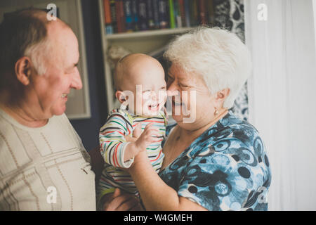 Glückliche Großeltern ihre Enkel baby Holding Stockfoto