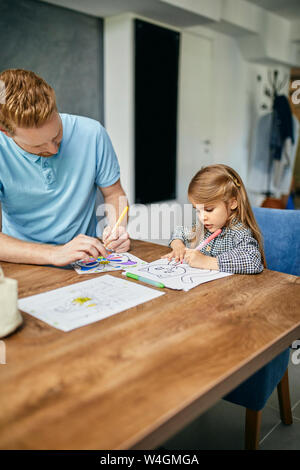 Vater und Tochter am Tisch sitzen, malen Buch Färbung Stockfoto