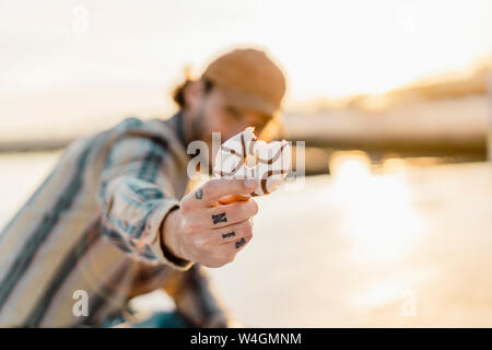 Man tätowierten Hand gebissen Donut bei Sonnenuntergang, close-up Stockfoto