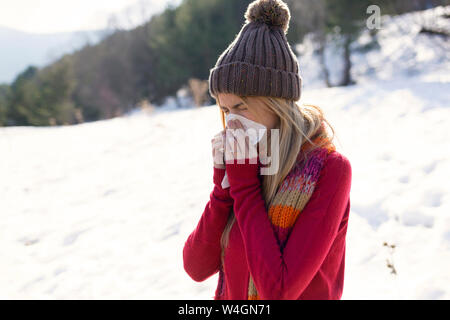 Junge blonde Frau blasen Nase im Winter Stockfoto