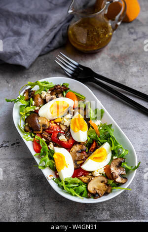 Rucola mit gebratenen Champignons, hart gekochte Eier, Tomaten und Feta Stockfoto