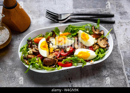 Rucola mit gebratenen Champignons, hart gekochte Eier, Tomaten und Feta Stockfoto