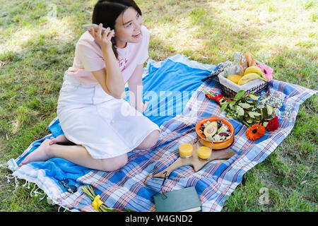 Entspannt Frau mit Handy und bei einem Picknick im Park Stockfoto